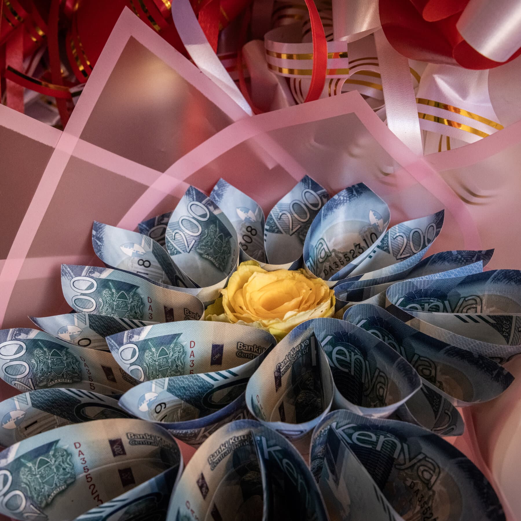 A single, wilted flower where the petals are made of crumpled, colorful banknotes, sitting in a glass of water on a scratched wooden table, high contrast, moody lighting, realistic style.