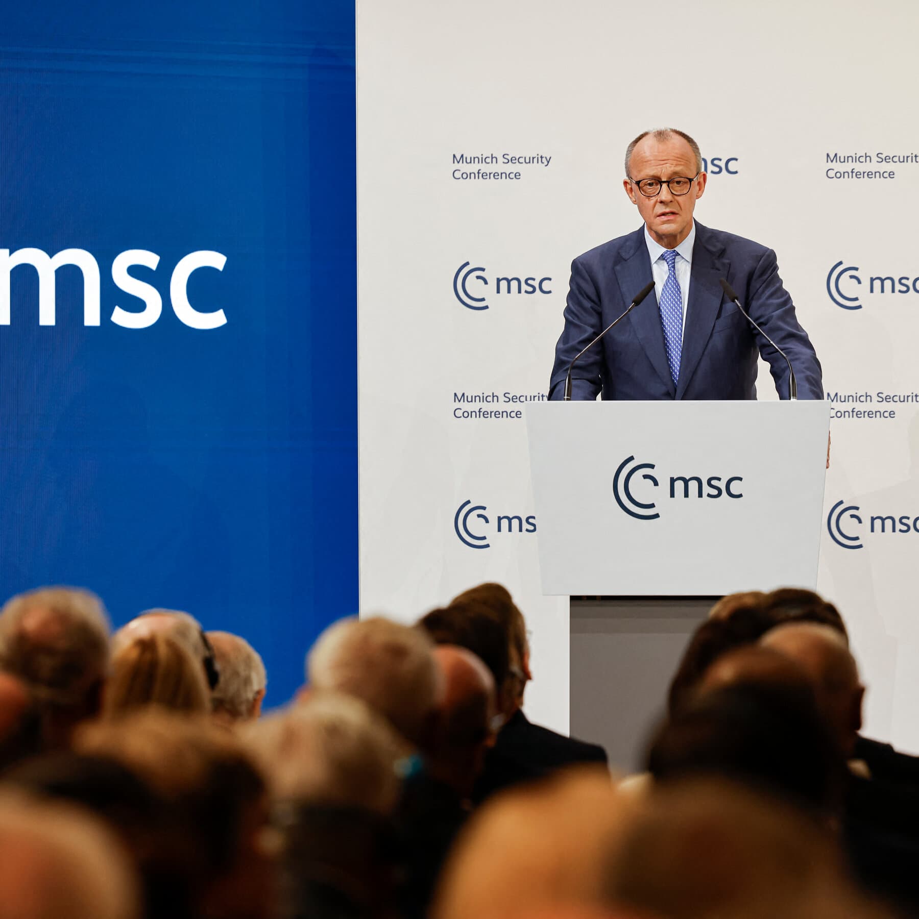 A hyper-realistic, gritty image of a bored man in a tuxedo sleeping at a conference table, with a nameplate that says 'LEADERSHIP'. In the blurry background, silhouettes of politicians are arguing aggressively. The lighting is dim and cold, blue and grey tones.
