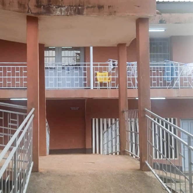 A gritty, noir-style illustration of a chain-link fence at night with a large, unmarked airplane in the background. In the foreground, a broken camera lens lying on dirty pavement under a harsh streetlamp. High contrast, muted colors, cynical atmosphere.
