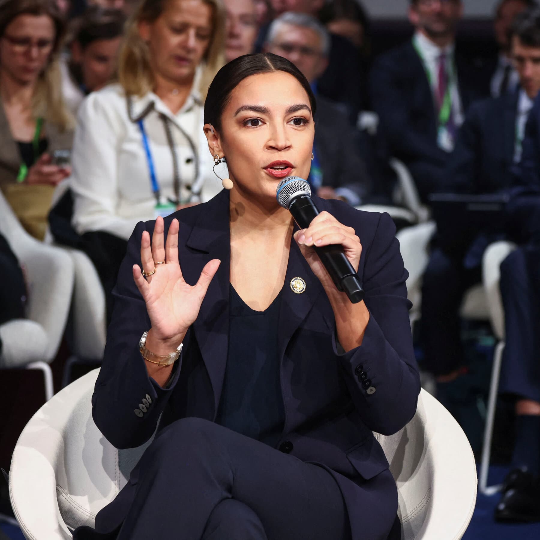 A satirical illustration of American politicians standing on a stage in a European city, looking through binoculars back at a map of the United States, while confused Europeans look on in the background. The style should be gritty and slightly caricatured.