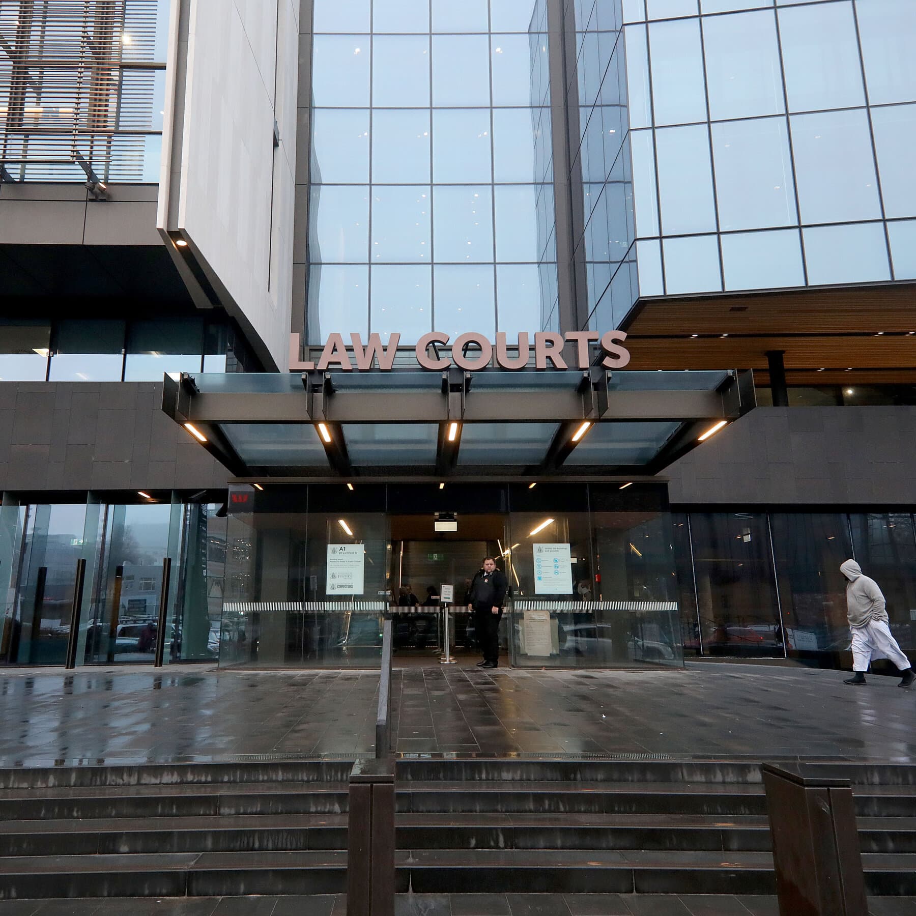 A gritty, noir-style courtroom sketch showing a robot in a suit standing at the defendant's podium wiping a fake tear from its metal face, while a bored human judge looks down with disdain. Muted colors, dark atmosphere.