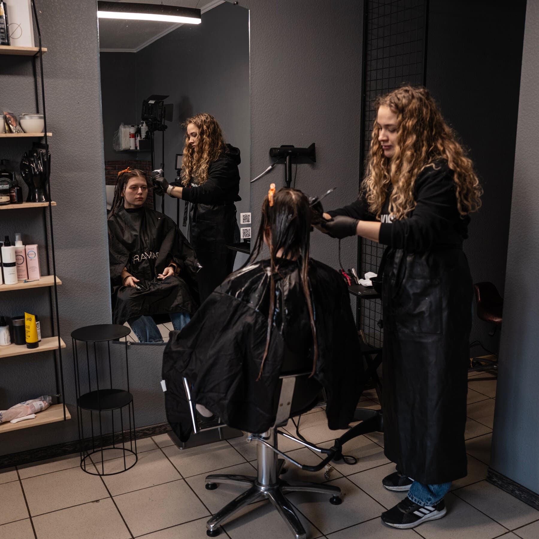 A single, battered suitcase standing alone on a cracked dirt road, with a blurry, gray, war-damaged apartment block in the background under a gloomy overcast sky. Realistic, gritty style.