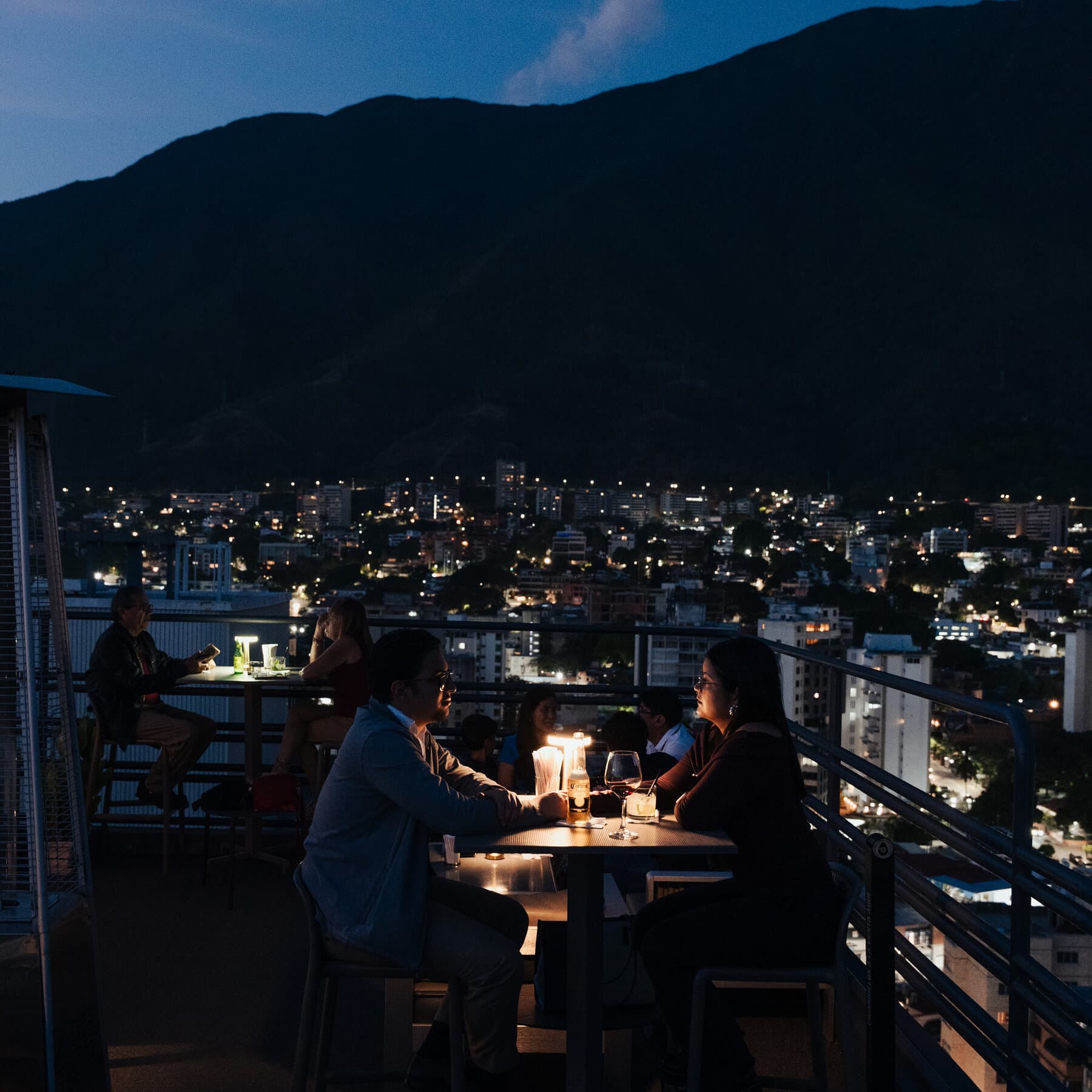 A high-contrast, noir-style illustration of a sleek, modern luxury sports car parked on a cracked, crumbling street at night. Neon lights from a glitzy nightclub reflect in the dirty puddles on the road. In the shadows outside the light, indistinct figures of stray dogs and people in rags can be seen. The atmosphere is cynical and divides wealth and ruin.