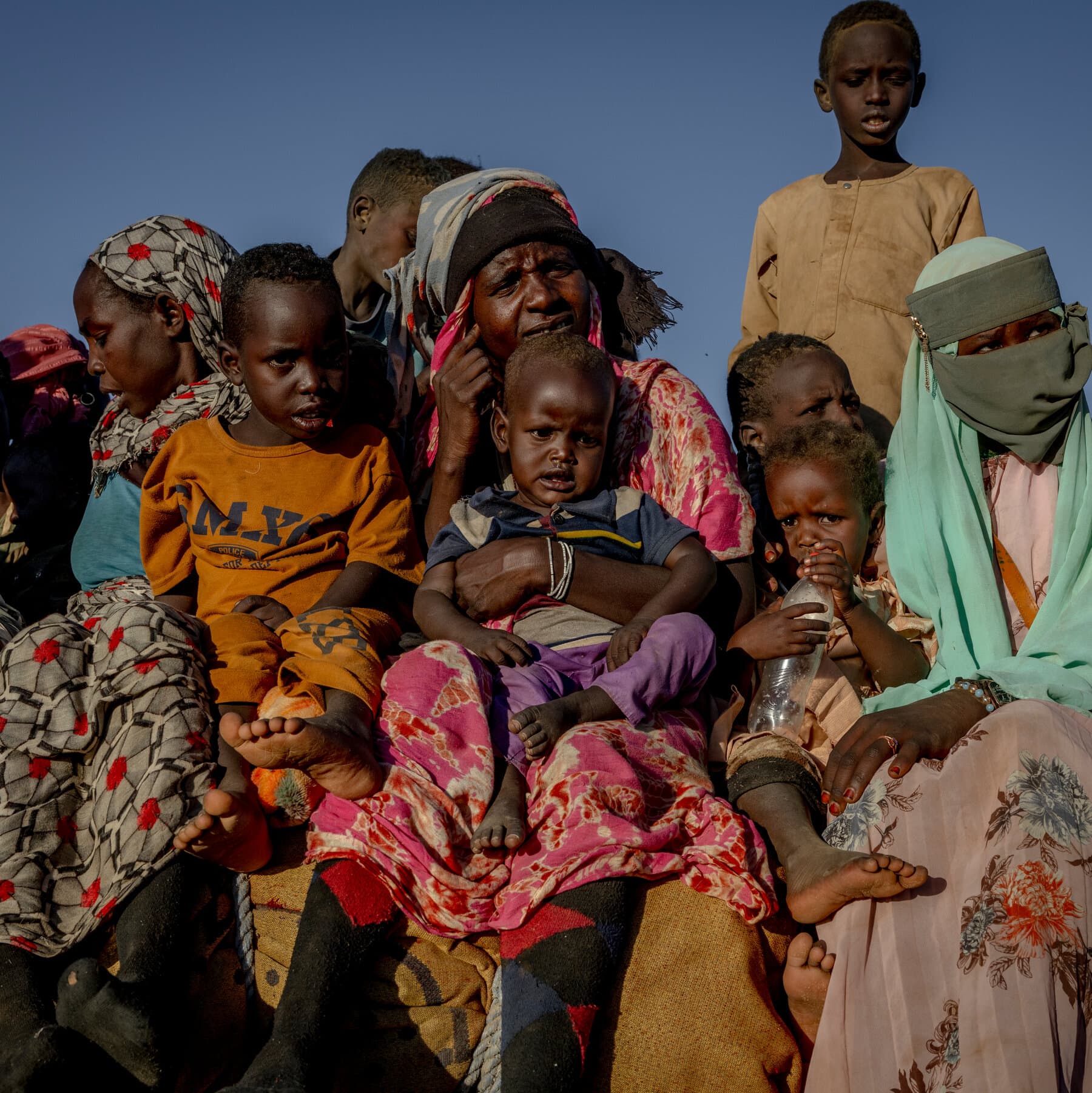 A hyper-realistic, high-contrast image of a pristine, white United Nations report folder lying in the red dust of a desert. The folder is stamped with the word 'OBSERVED' in red ink. In the blurred background, the silhouette of a ruined city under a scorching sun. The style should be gritty and cinematic, emphasizing the contrast between bureaucratic paper and harsh reality.