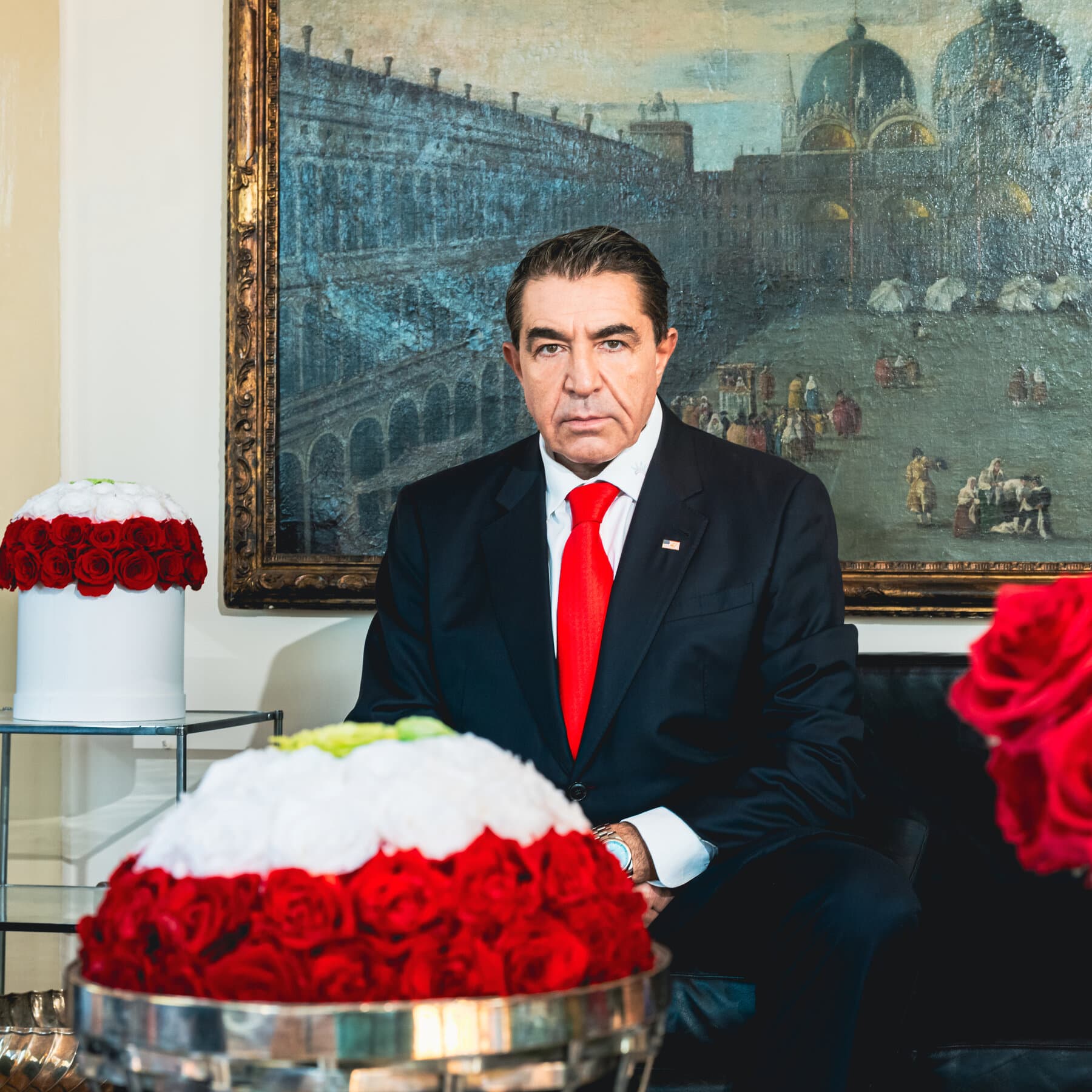 A conceptual editorial illustration showing a chessboard where the pieces are replaced by sports trophies and toy soldiers. A hand in a business suit is knocking over the pieces while another hand holding a European Union flag gestures in shock. The background is a dark, moody grey with a spotlight on the chaotic board.