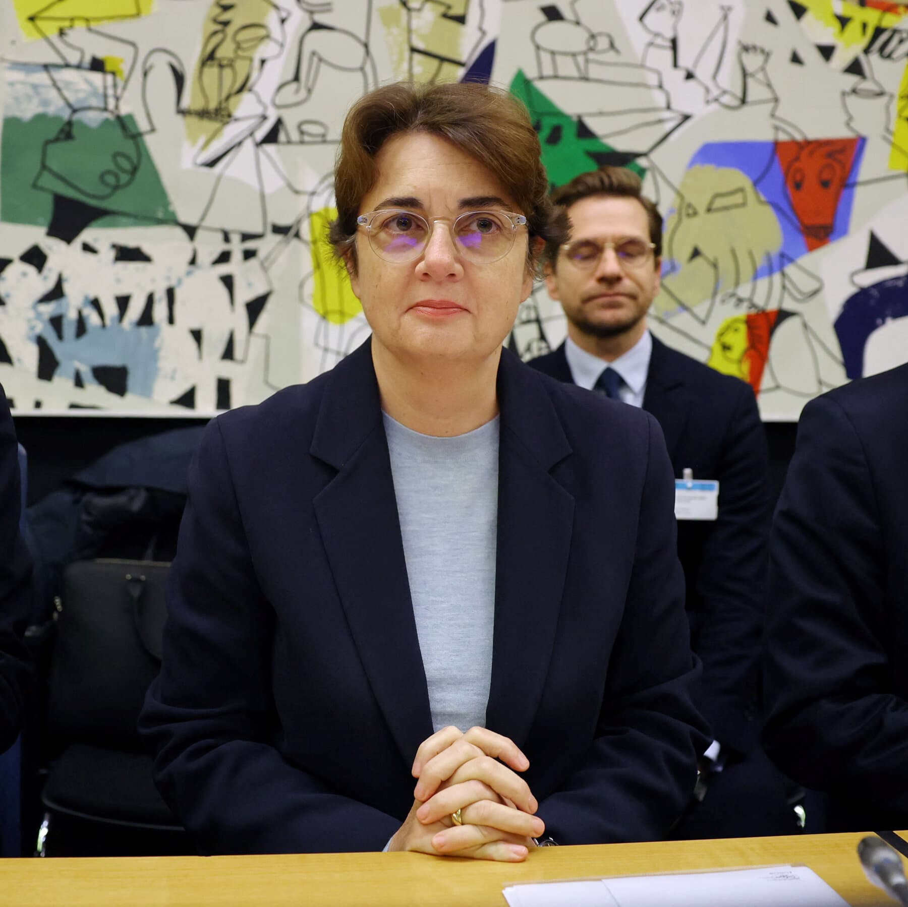 A gritty, high-contrast photo of the Louvre glass pyramid at night, looking ominous and neglected. In the foreground, there is yellow caution tape fluttering in the wind and a puddle of dirty water on the pavement reflecting a 'Closed' sign. The lighting should be dim and cold.