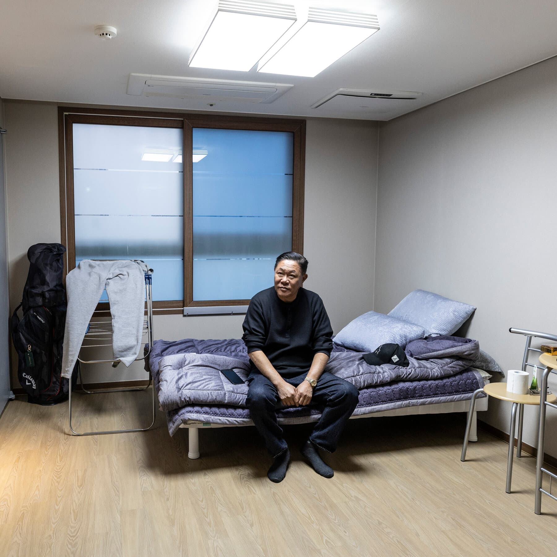 A tarnished Purple Heart medal lying abandoned on a cold, grey concrete floor, shadowed by a heavy stack of bureaucratic legal paperwork and a red DEPORTED stamp, high contrast, gritty style.