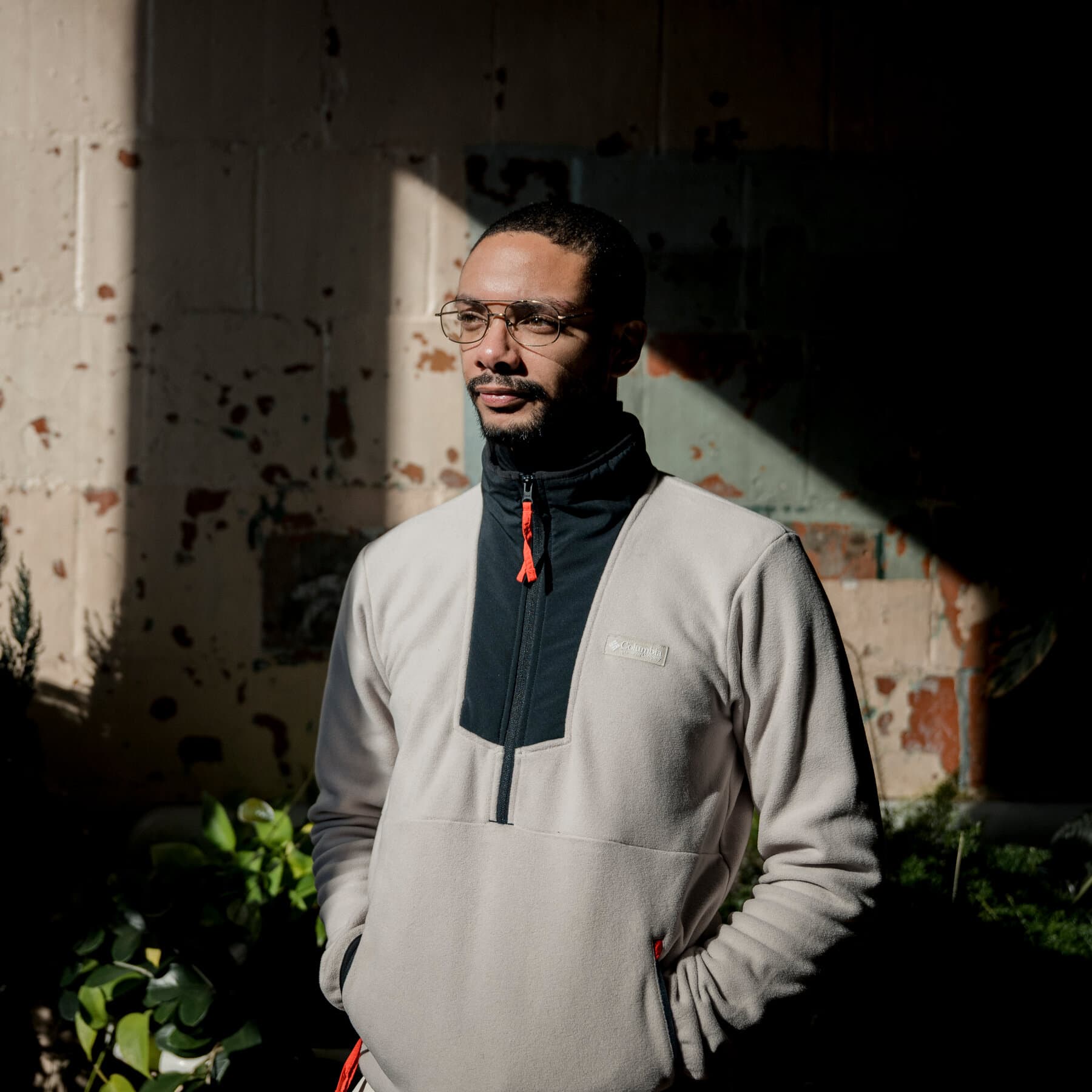 A gritty, high-contrast illustration of a tattered travel journal lying open on a dirty concrete prison floor. Beside the journal is a pair of rusted metal handcuffs. The lighting is dim and cold, casting long shadows that suggest prison bars. The style should be realistic but moody, emphasizing the contrast between the innocence of the journal and the brutality of the shackles.