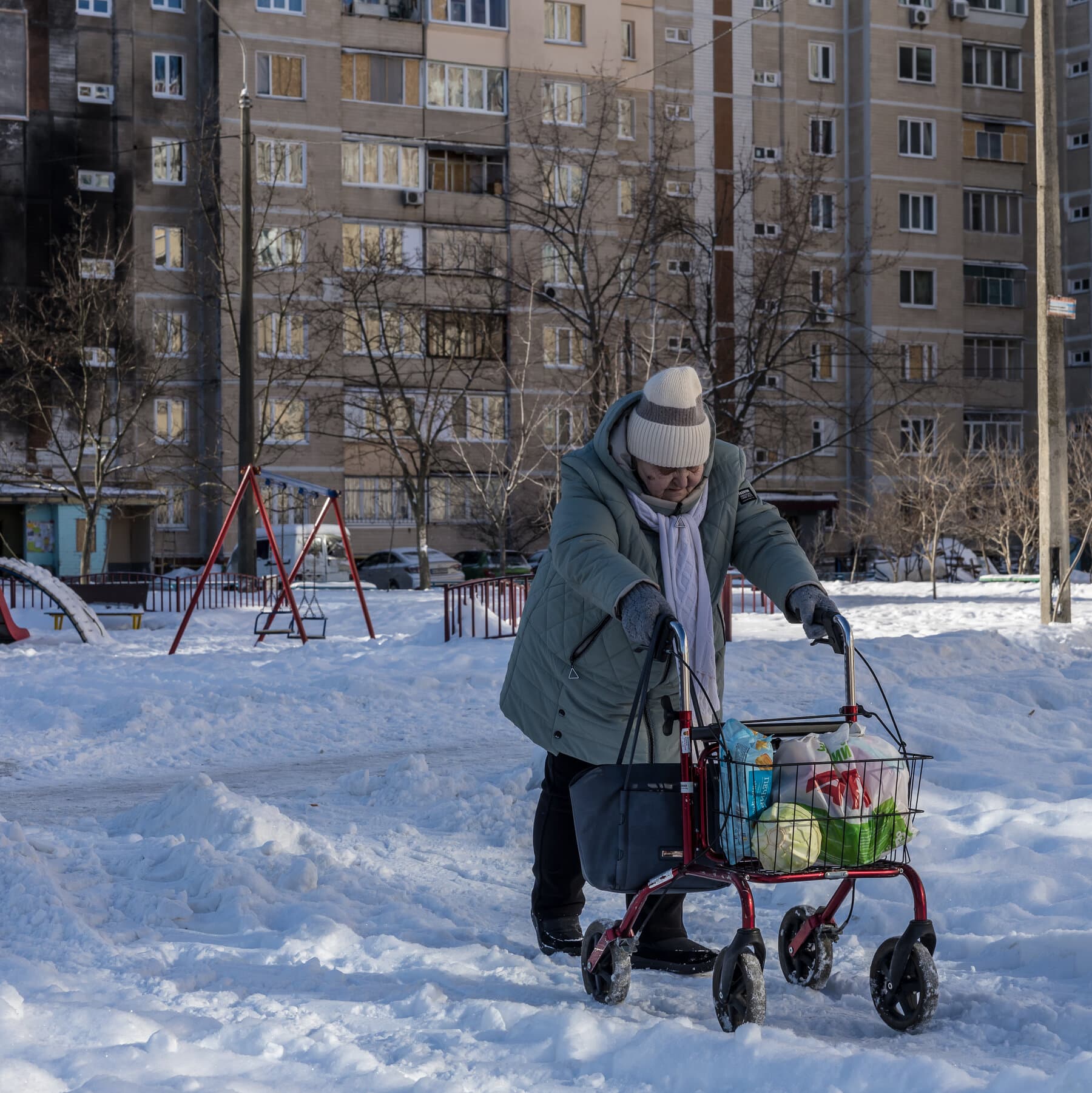 A hyper-realistic, gritty image of a worn-out theater stage. On the stage, a single, battered metal shield rests against a broken chair. The spotlight is harsh and unforgiving. In the background, faded blue and yellow curtains are torn and dusty. The atmosphere is cold, cynical, and exhausted, reflecting a sense of abandonment and weary endurance.