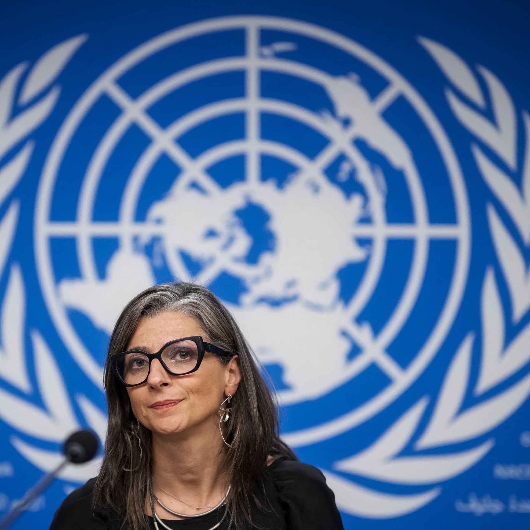 A weary-looking woman standing in front of a massive, crumbling stone courthouse, holding a single piece of paper, while giant shadowy hands in suits point at her from above, style of cynical political art, grey and muted tones.