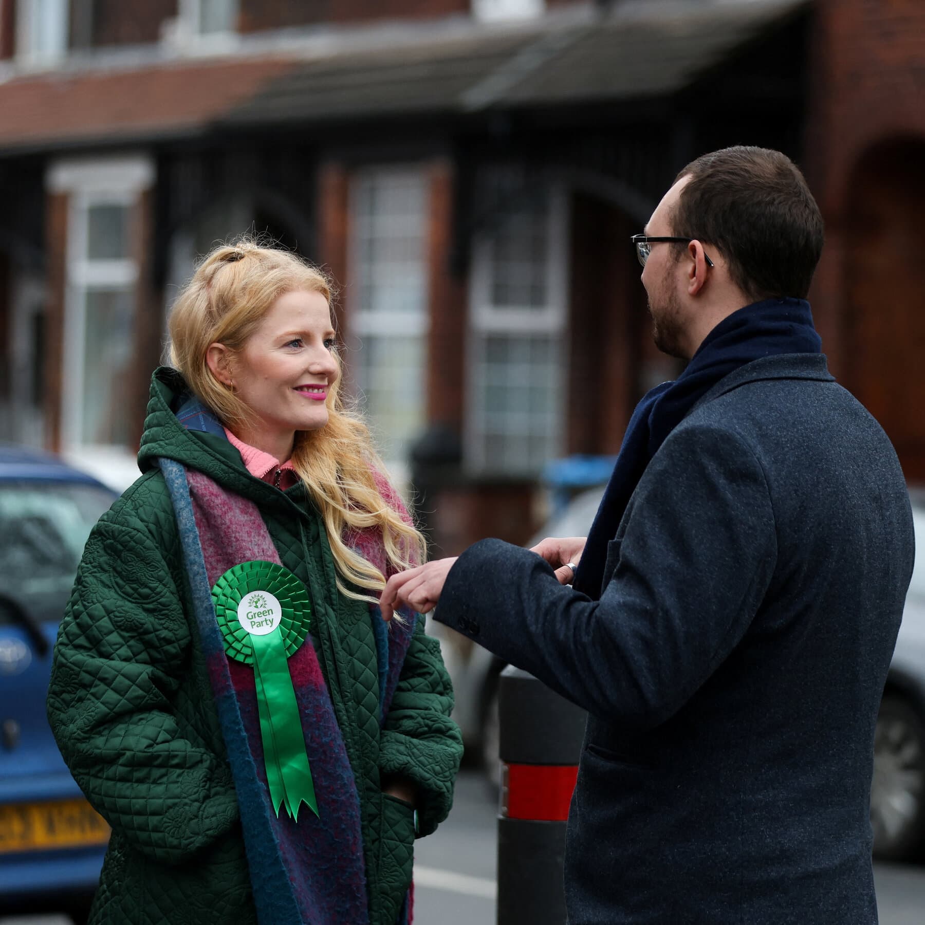 A hyper-realistic satire illustration of UK Prime Minister Keir Starmer standing in a grey, rainy British street looking confused, holding a wilted red rose, while a bright green vine grows aggressively over the pavement and cracks the concrete, style of political caricature, gloomy atmosphere, cinematic lighting.