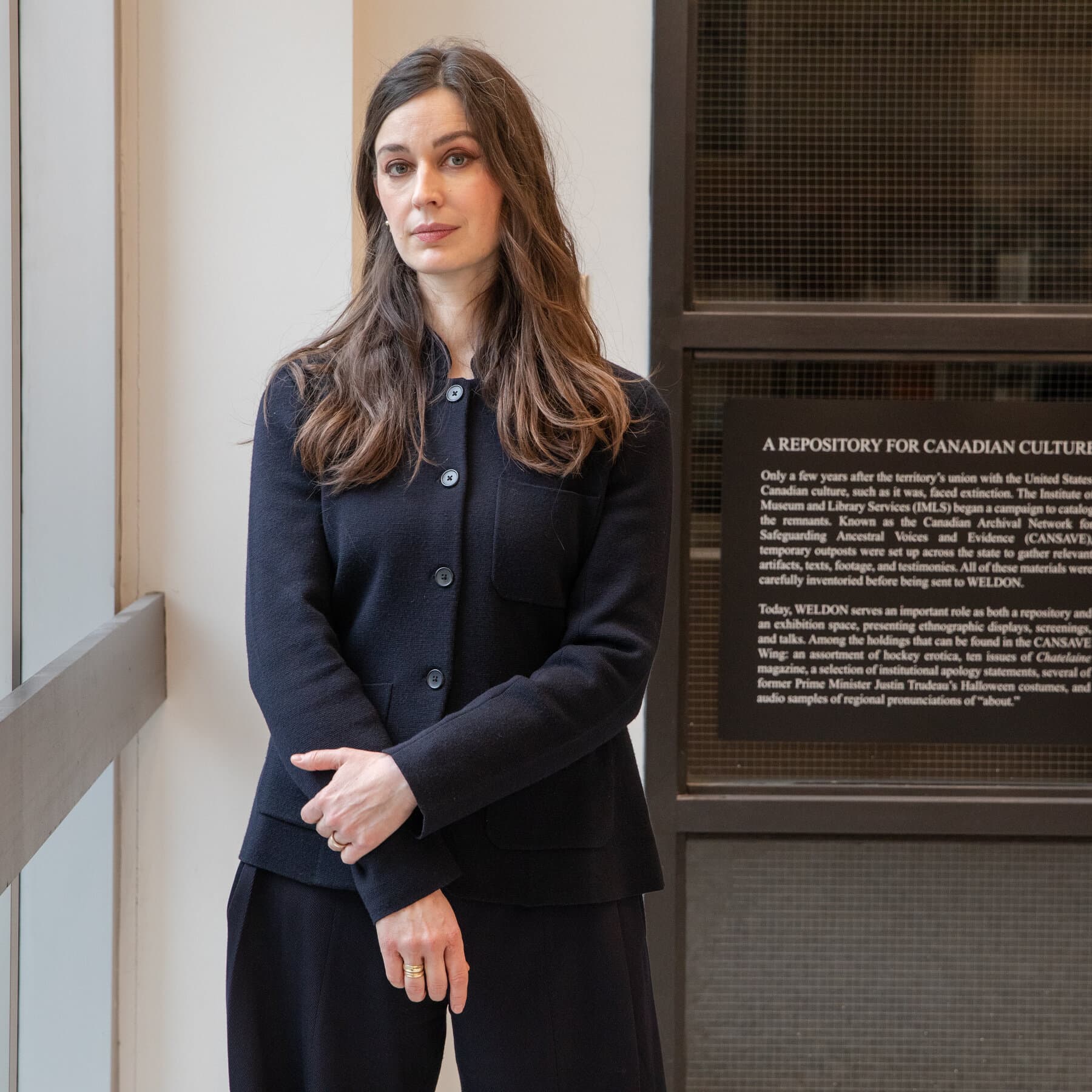 A gritty, overcast alleyway in Toronto featuring a weathered, torn poster pasted on a brick wall. The poster displays a fictional, dystopian government seal combining American and Canadian symbols, looking authoritarian and bureaucratic. The atmosphere is cold, urban, and cynical.