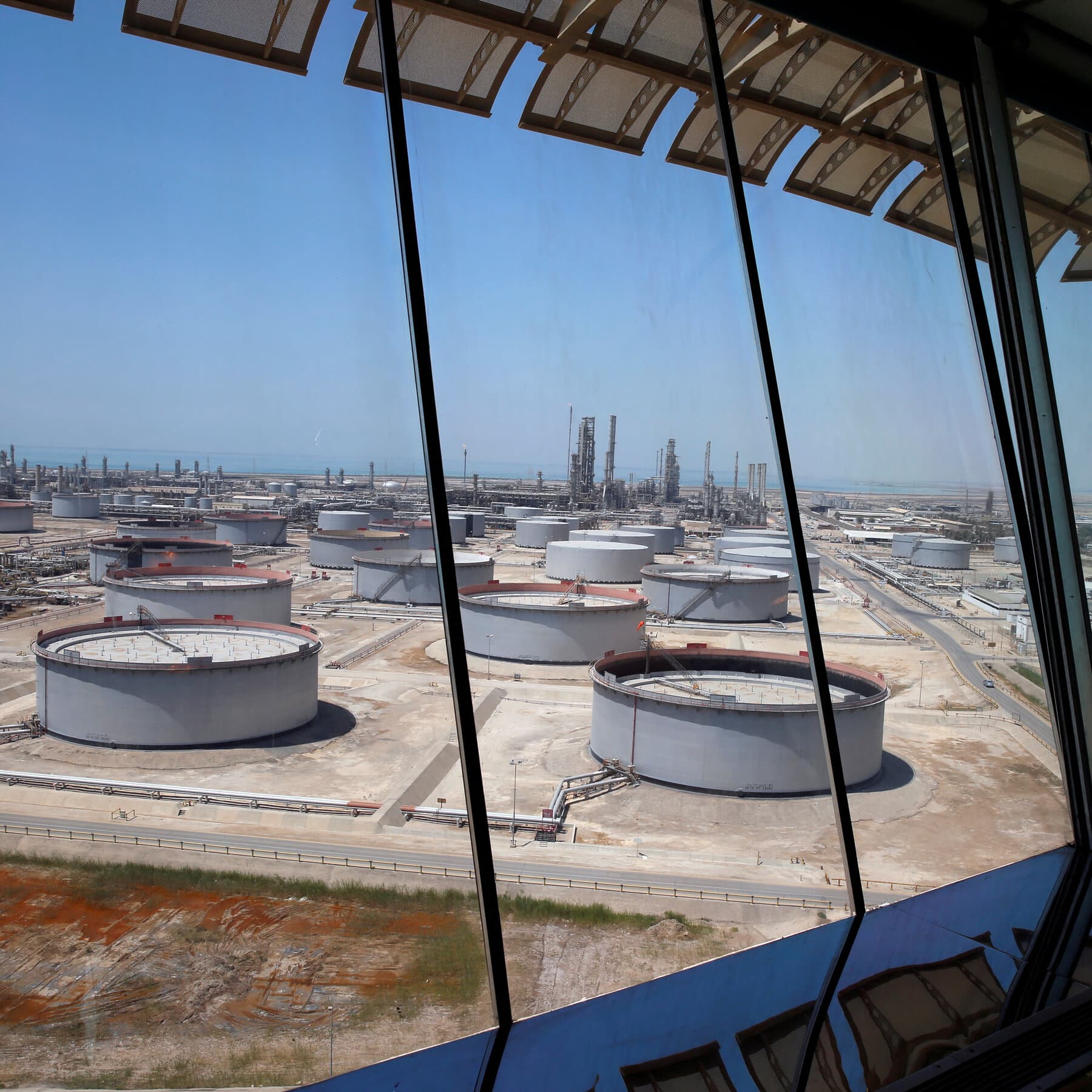 A gritty, cynical illustration of a gas pump nozzle turned into a snake, wrapping around a helpless consumer's wallet. In the background, vague silhouettes of men in suits shaking hands while oil rigs burn in the distance. The style should be dark, satirical comic book art.