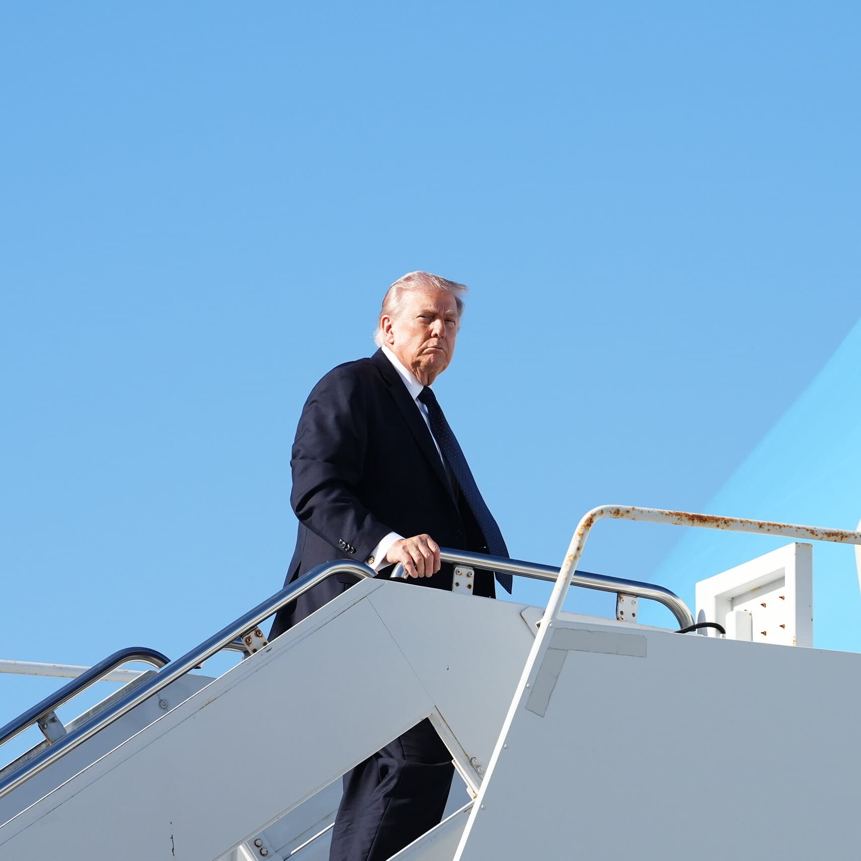 A surreal, satirical illustration in the style of a political cartoon. A large, ornate hourglass sits in the middle of a desert. Inside the hourglass, instead of sand, there are tiny toy soldiers falling through. Standing next to it is a caricature of a suit-wearing politician looking at a pocket watch with a bored expression. In the background, a mirage of a peaceful city shimmers, while the foreground is cluttered with discarded military helmets. The sky is a hazy, cynical grey-orange.
