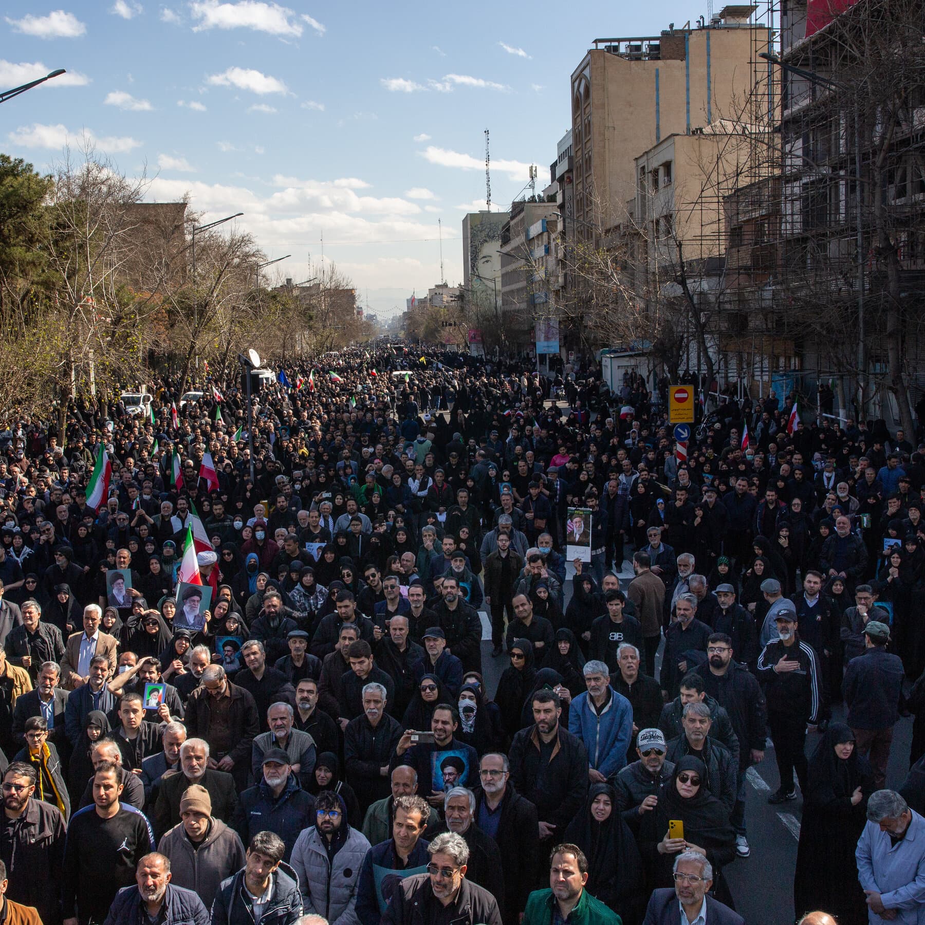 A split composition: on the left, a crowd of people in modern street clothes cheering and holding sweets at night; on the right, a crowd of people in black traditional clothing weeping and holding candles. In the background, a vague, ominous smoke plume rises into a grey sky. Digital art style, gritty and high contrast.