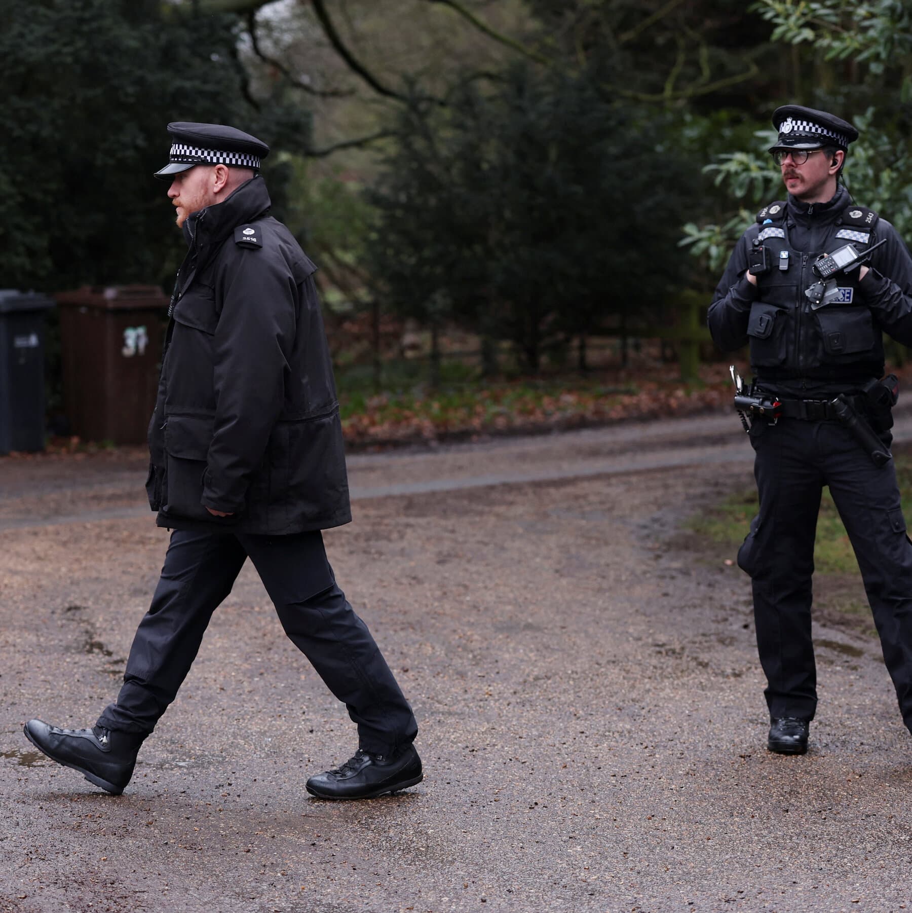 A gritty, high-contrast black and white illustration in a noir style. In the foreground, a large pile of shredded American legal documents and red tape sits on a desk. In the background, out of focus, a European police officer is placing handcuffs on a man in a suit. The lighting is dim and cynical.