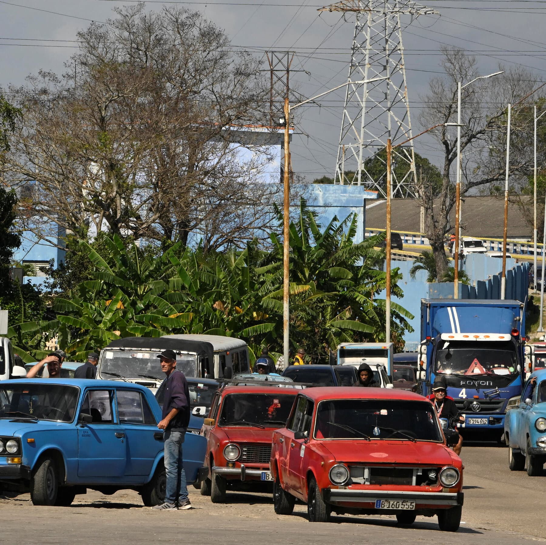 A conceptual illustration of a vintage 1950s car in Havana, rusted and worn, parked under a dark, looming storm cloud shaped like the blurred profile of a shouting politician. The colors should be faded and gritty.