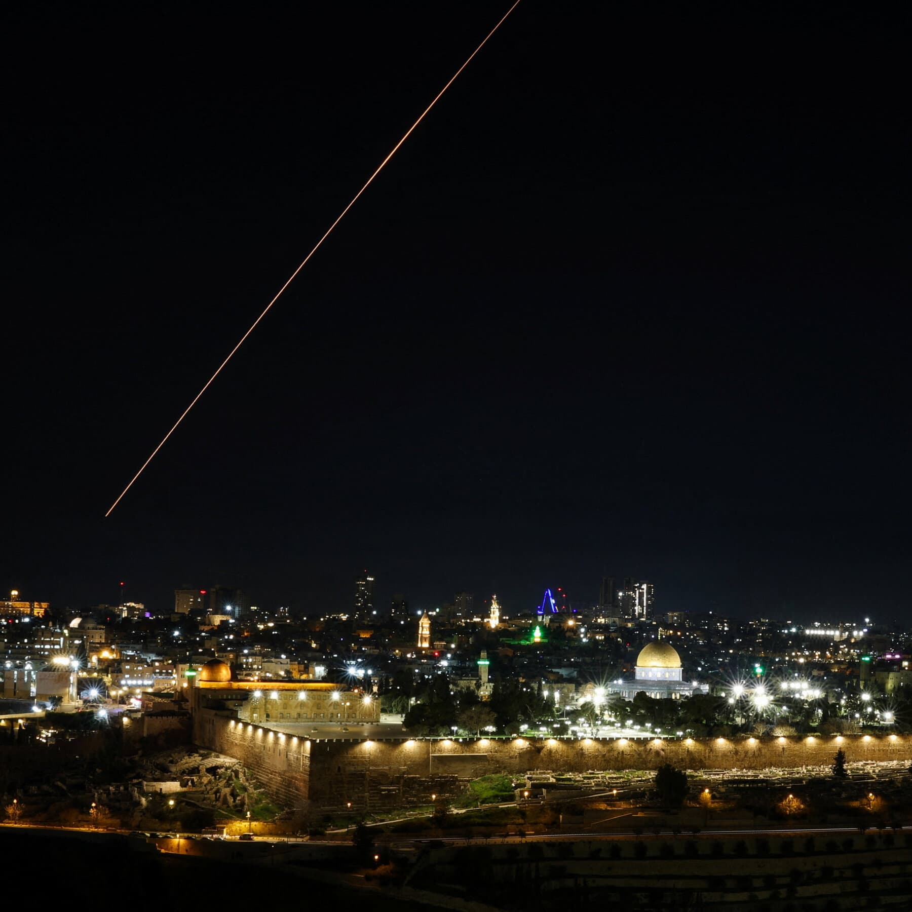 A high-contrast, black and white image of a heavy, ancient wooden door secured with a modern, cold steel padlock. In the foreground, blurry silhouettes of people are waiting, while the background shows a stark, empty stone courtyard under a harsh, gray sky.