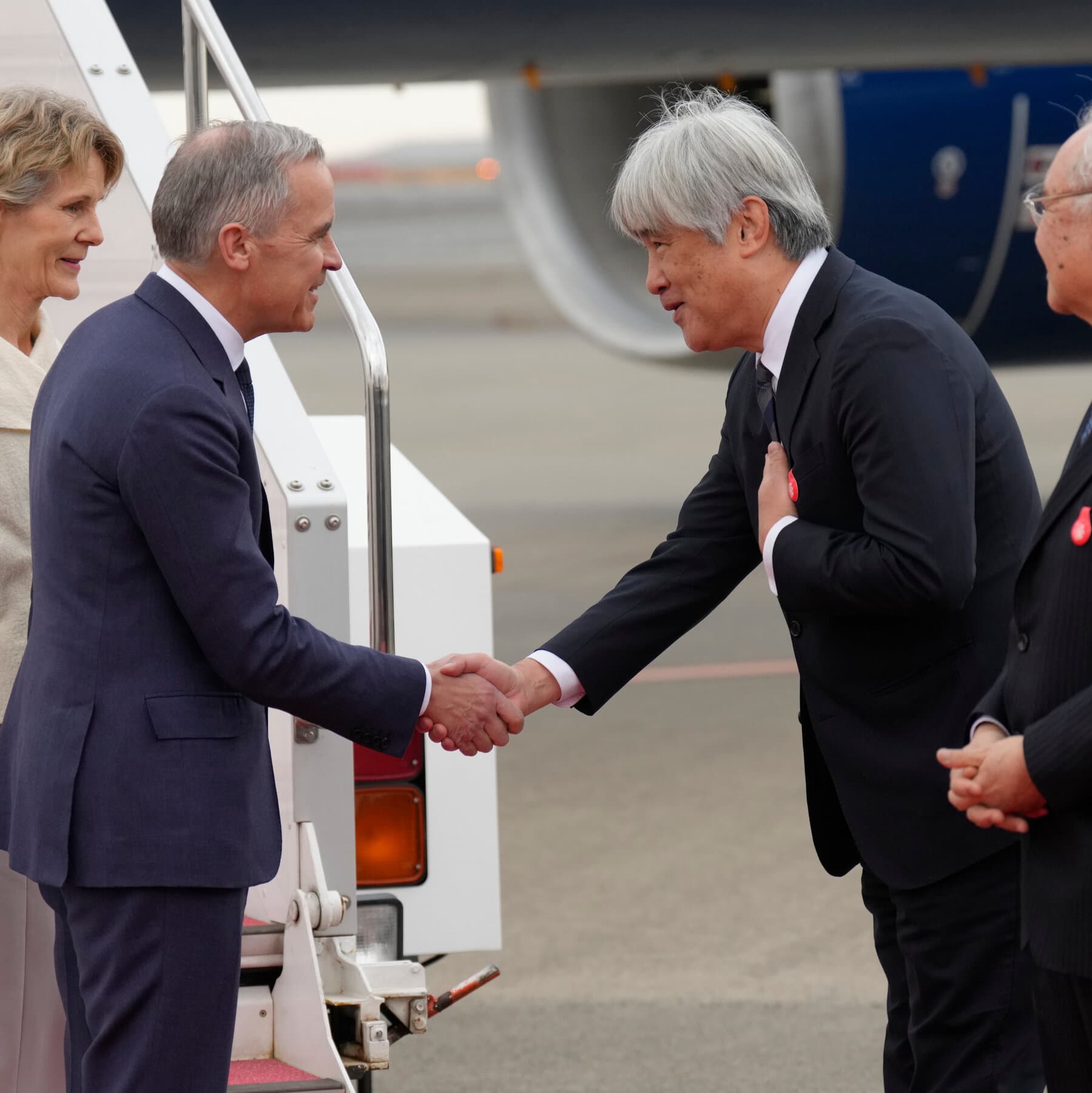 Justin Trudeau and the Japanese Prime Minister looking confused and scared while holding a broken toy shield, political cartoon style, dark grey background, stormy weather.
