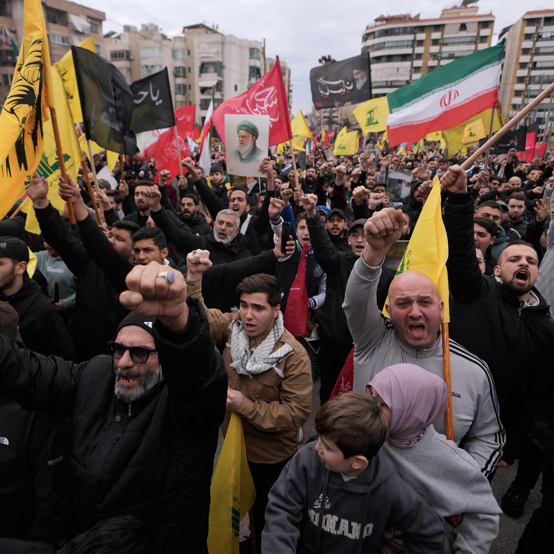 A gritty, high-contrast black and white photojournalism style image of a broken plastic chair sitting alone in the middle of a rubble-filled street in Beirut. In the background, faded and torn election posters hang from a wall riddled with holes. The lighting is harsh and unforgiving. No people are visible, just the debris of a city that has seen this all before.