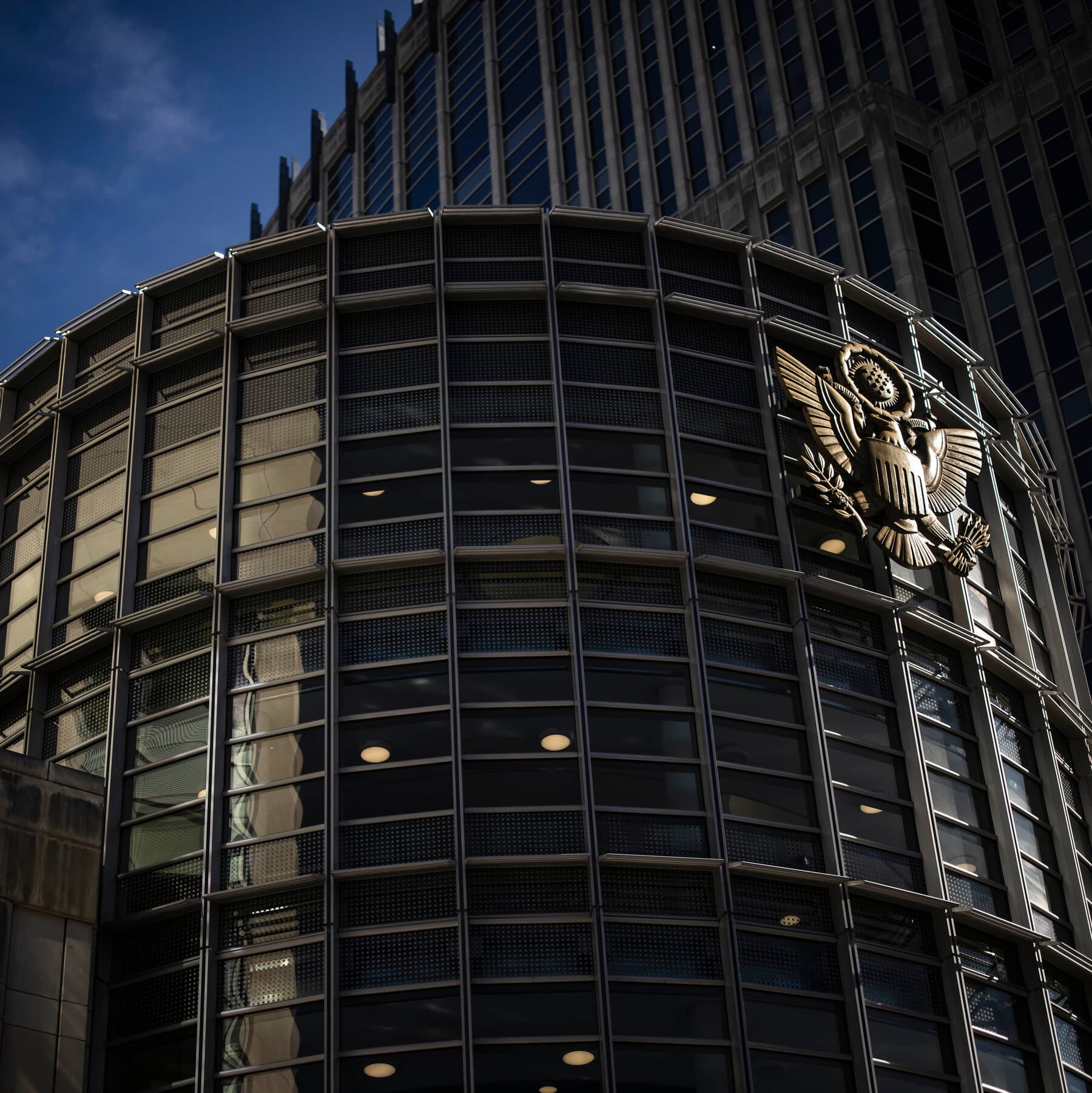 A moody, high-contrast charcoal sketch of a lonely, empty federal courtroom in Brooklyn. Shadows stretch long across the wooden benches. In the center, a small, indistinct figure stands before a massive, looming judge's bench, symbolizing the crushing weight of the system. The atmosphere is cold, bureaucratic, and cynical.
